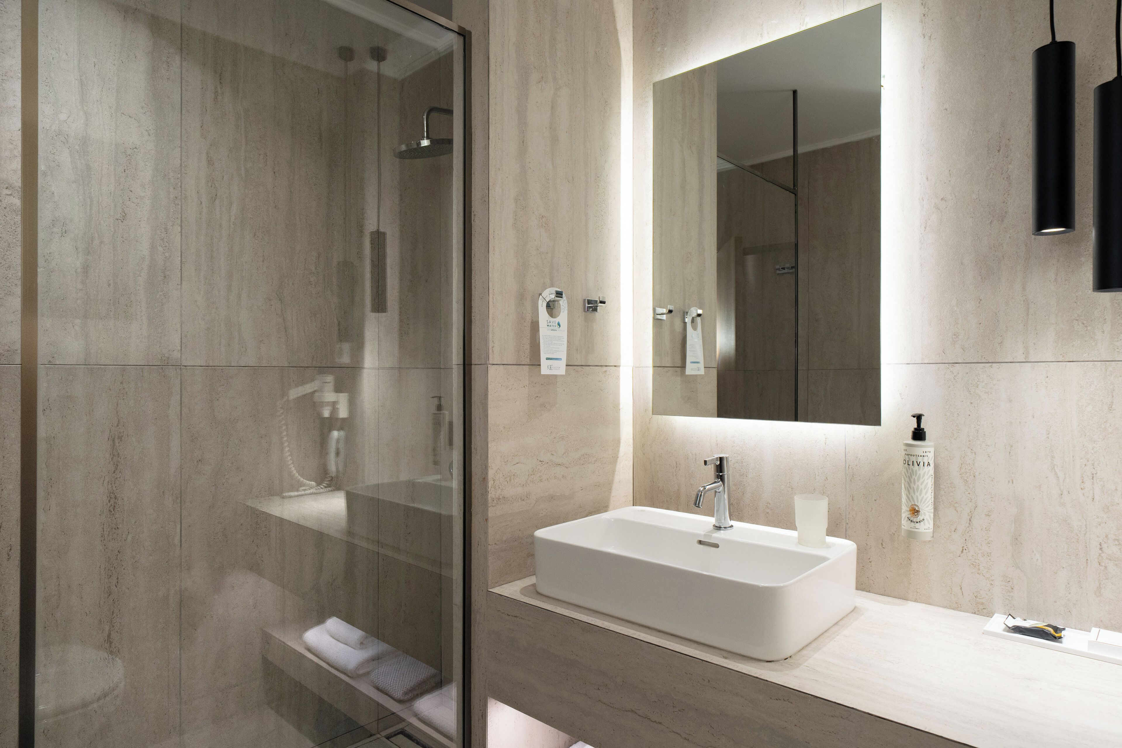 A modern bathroom with a glass shower enclosure, a white sink, and a large mirror.