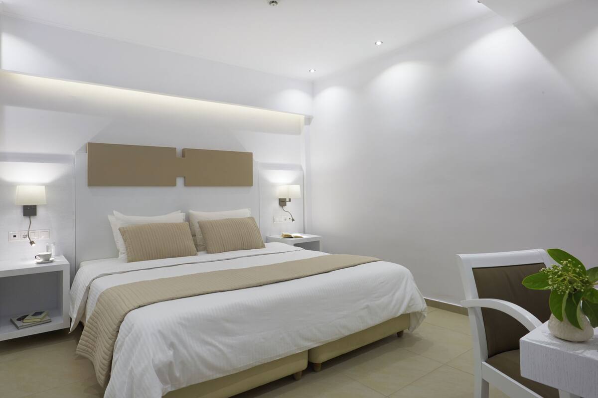 A modern bedroom with a large bed, bedside tables, a nightstand, and a chair.