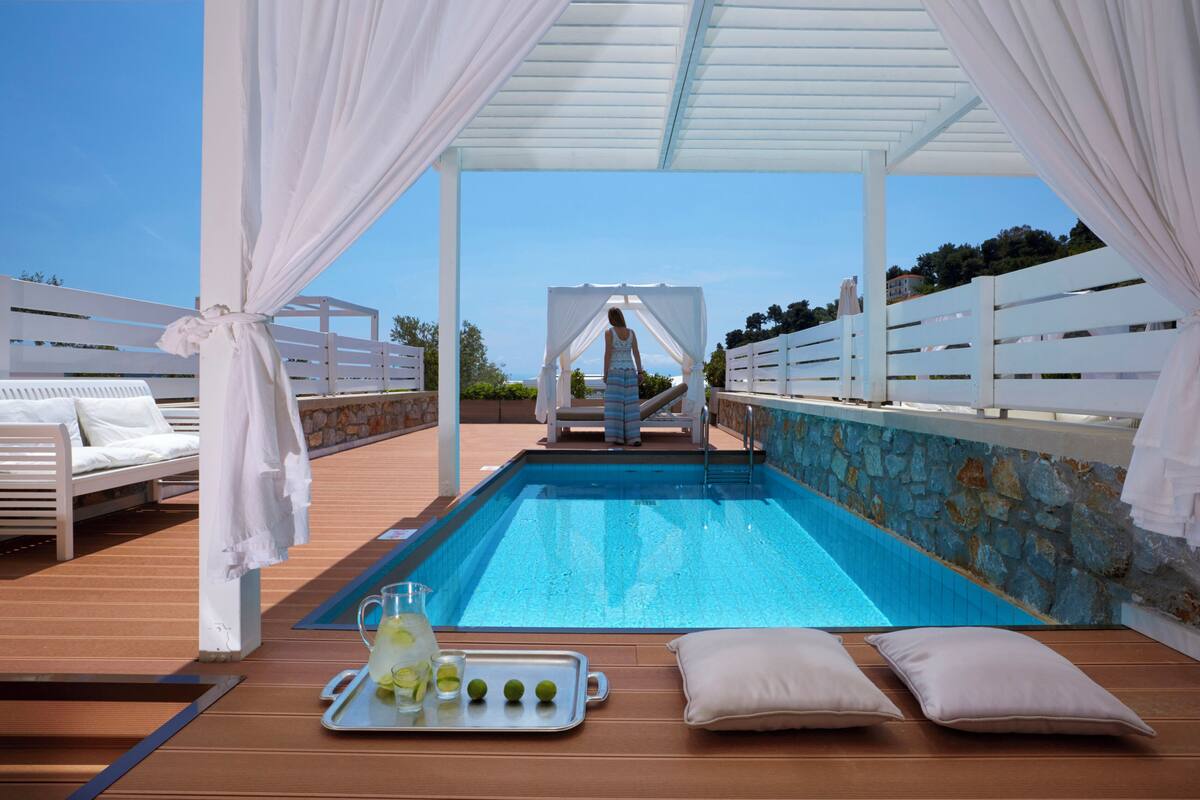 A pool area with a canopy, lounge chairs, and a tray with drinks.
