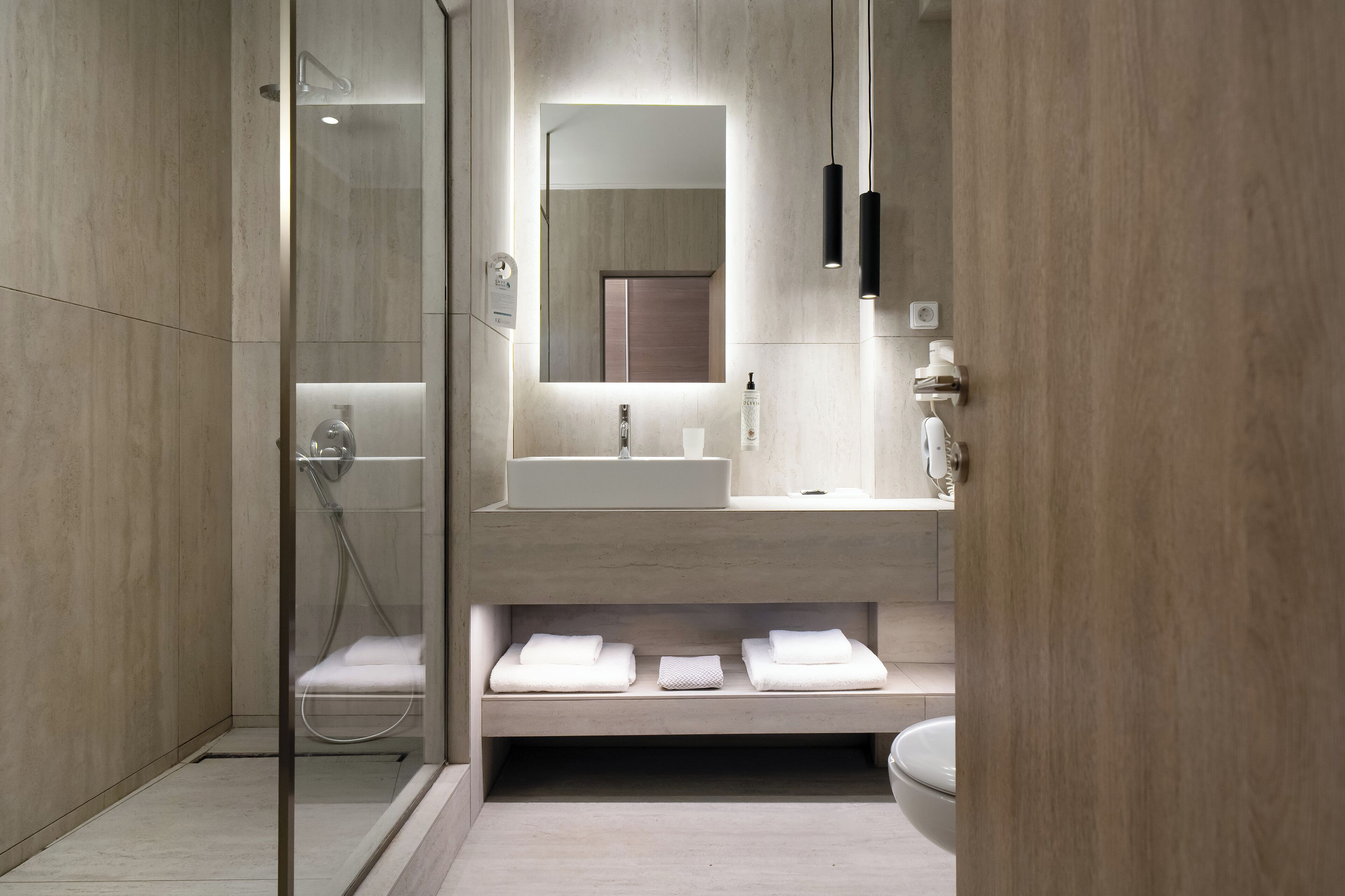 A modern bathroom with a glass-enclosed shower, a large mirror, and a vanity with a sink and towel storage.