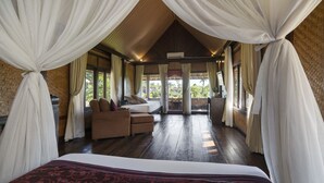 Ruime kamer met een groot bed, een slaapbank en een tafeltje. Gordijnen en uitzicht op het omliggende landschap.