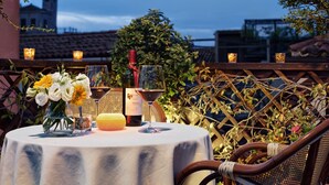 A round table with a white tablecloth, a bottle of wine, a glass of wine, a candle, and a vase of flowers. - Hotel Antica Locanda Al Gambero (Venice)