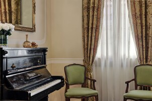 A piano, two chairs, a mirror, and curtains in a room.