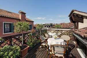 A terrace with wooden furniture, a table, and potted plants.