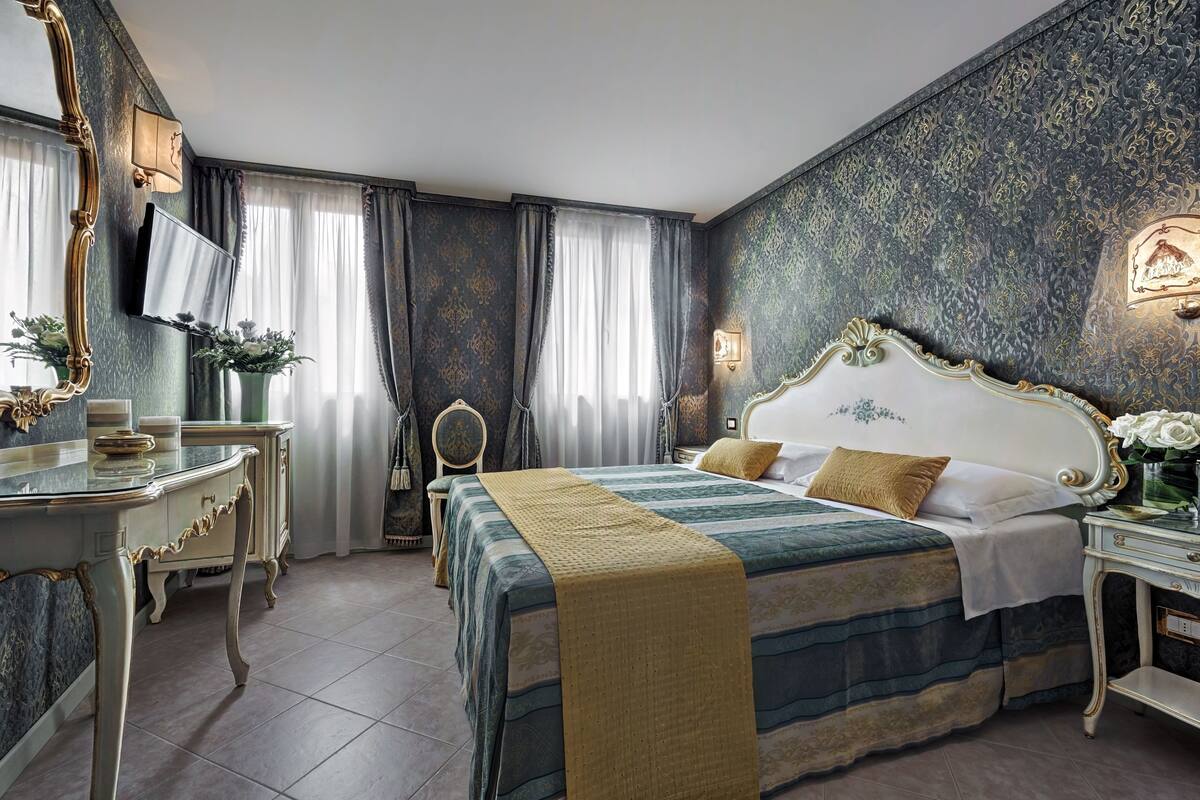 Een slaapkamer met een groot bed, een dressoir, een kaptafel en een televisie.