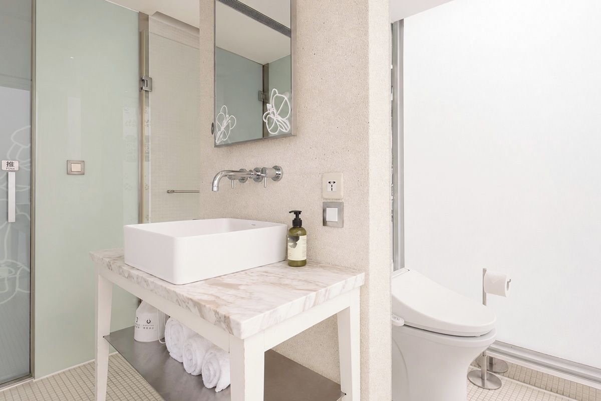 A bathroom with a white sink, mirror, and toilet.