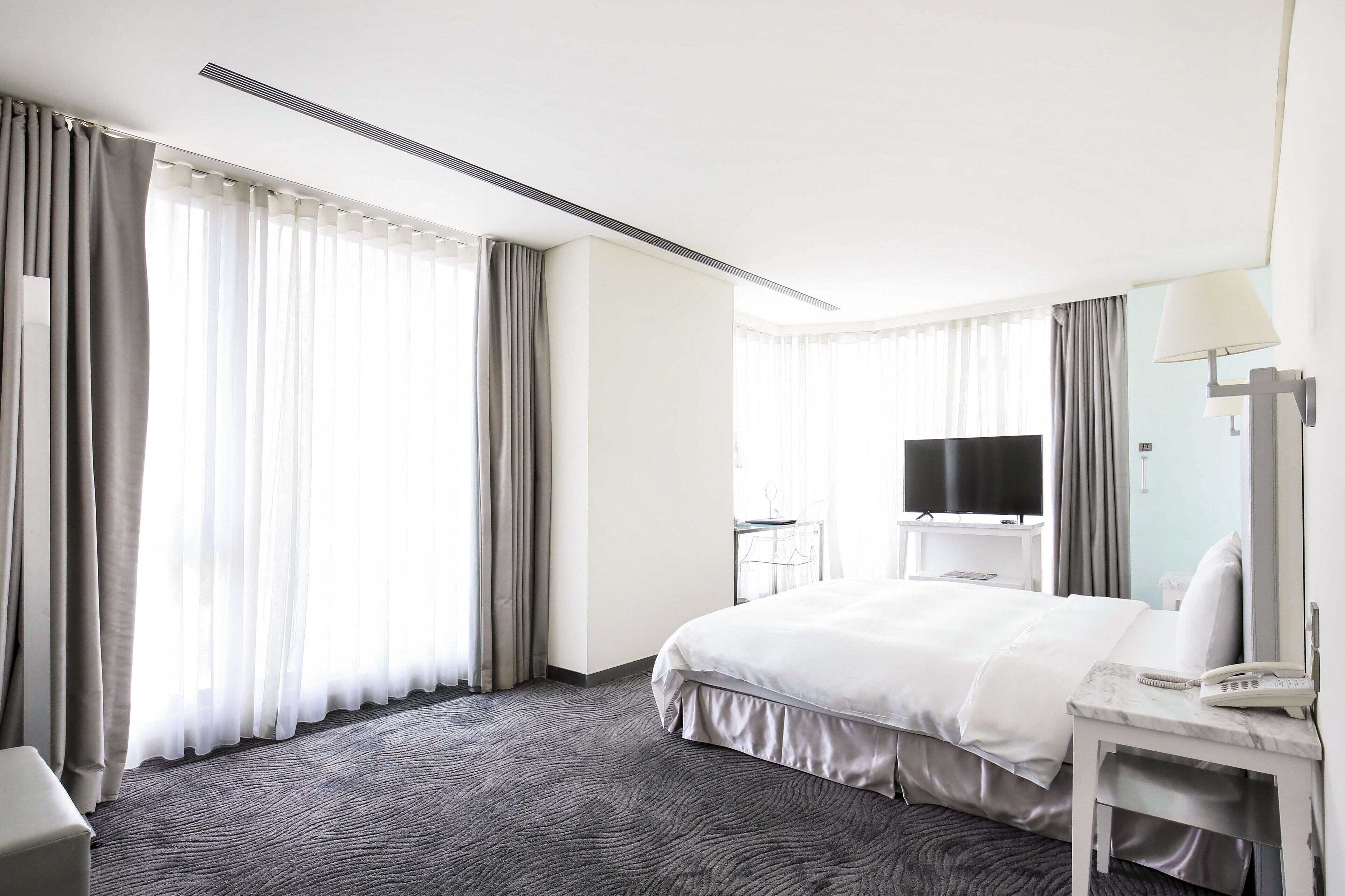 Een hotelkamer met een groot bed, een bureau met lamp, een televisie en een telefoon.