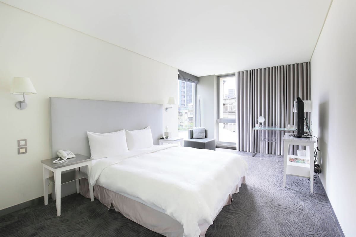 Een moderne hotelkamer met een groot bed, nachtkastjes, een bureau en een televisie.