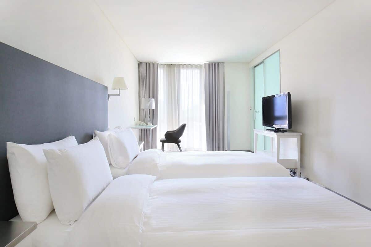 Een hotelkamer met twee bedden, een televisie, een bureau en een stoel.