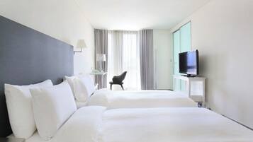 Habitación de hotel con dos camas, un televisor, un escritorio y una silla.