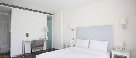 Habitación de hotel con una cama grande, un escritorio, una silla y dos mesitas de noche con lámparas.