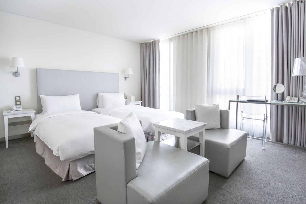 Een moderne hotelkamer met twee bedden, een bureau en een zithoek.