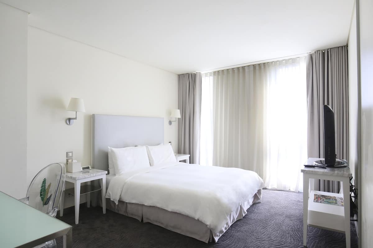 Een hotelkamer met een bed, nachtkastjes, een bureau en een televisie.