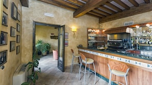 A bar area with wooden beams, a tiled floor, and bar stools. There are potted plants and a trash can visible. - Best Western Plus Hotel Le Rondini (San Francesco al Campo)