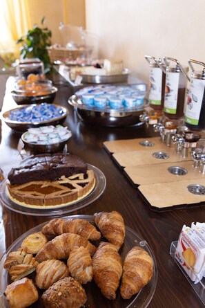 A buffet table with various food items including pastries, desserts, and beverages.