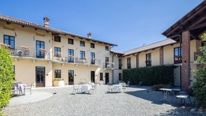A courtyard with outdoor seating, a building with multiple balconies, and a brick chimney. - Best Western Plus Hotel Le Rondini (San Francesco al Campo)