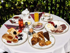 Enjoy a serene breakfast amidst lush greenery with a variety of dishes served on a beautifully set table.