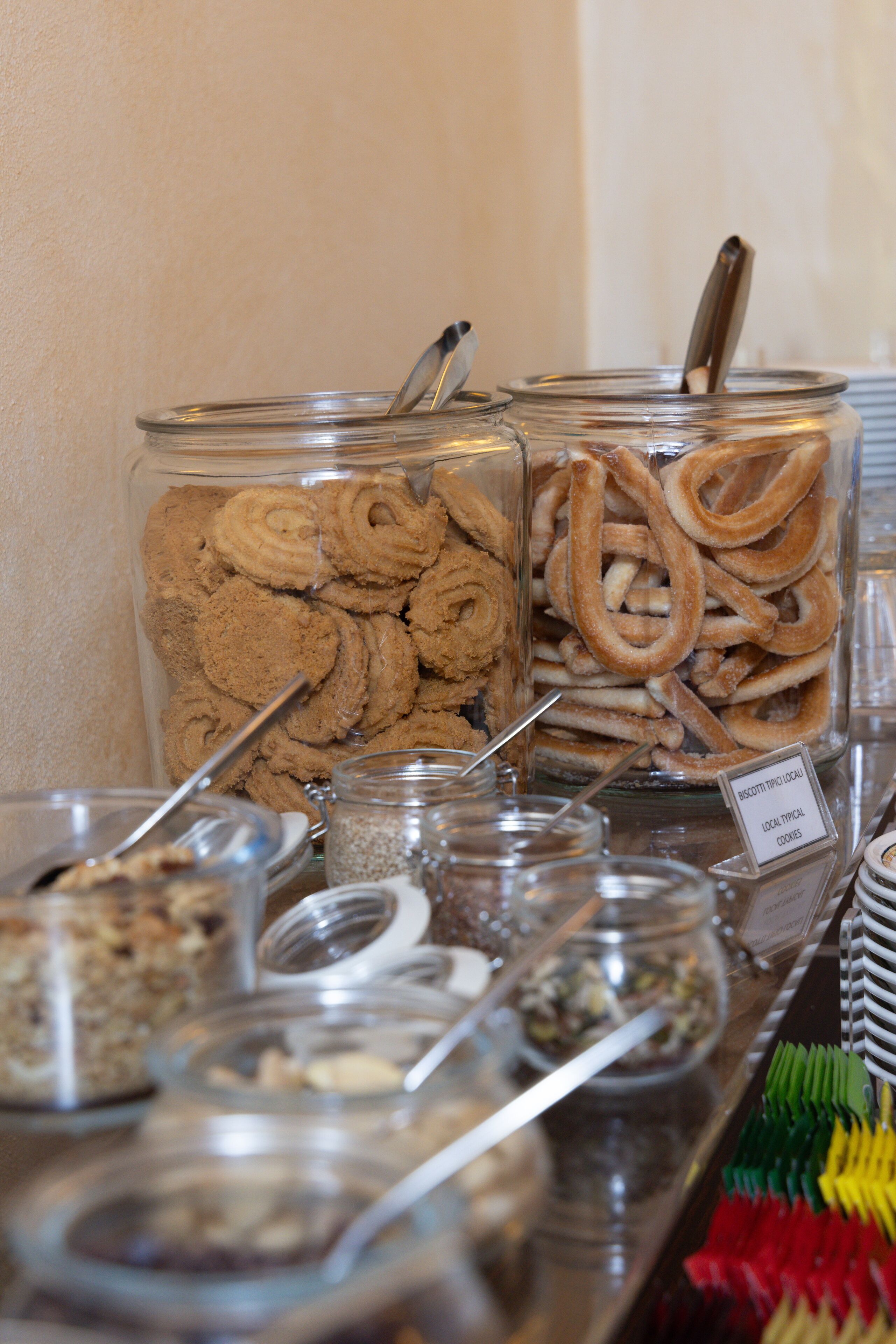 Un buffet proposant une variété d’aliments présentés dans des récipients en verre, notamment des biscuits et des bretzels.