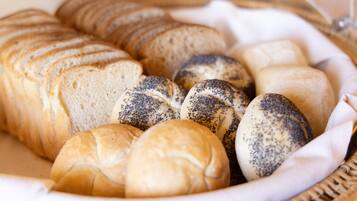 Una cesta con diferentes tipos de pan, incluyendo bollos y panes de semillas de amapola.