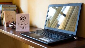 A laptop on a wooden desk with a sign reading "Internet Point" and a bowl of snacks.