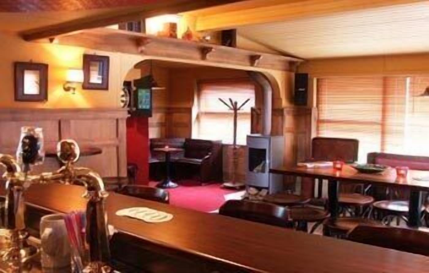 Un área de bar con mobiliario de madera, alfombra roja y chimenea.