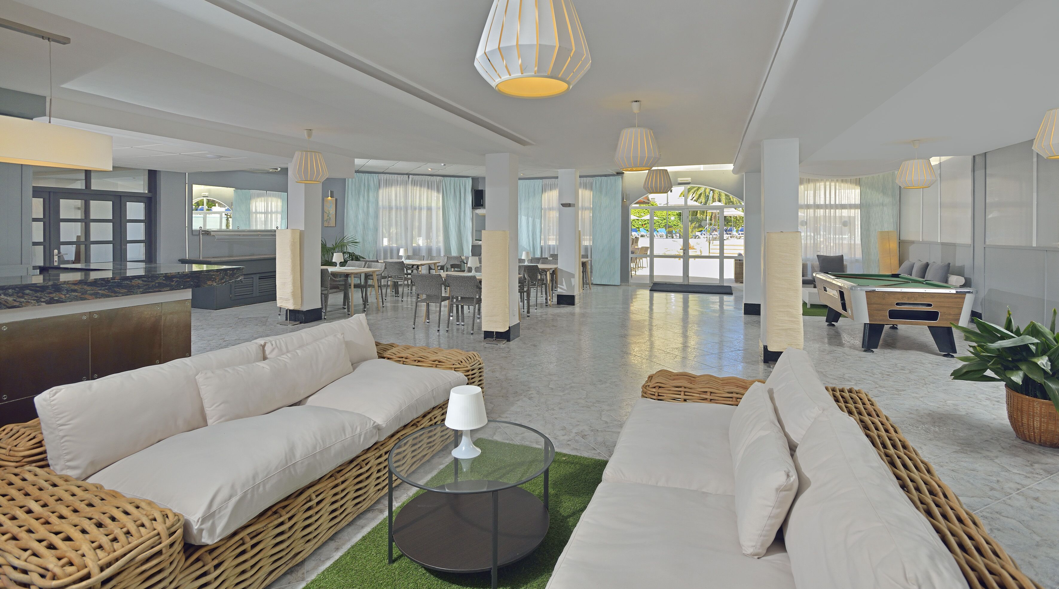 A spacious lobby with a pool table, comfortable seating areas, and a dining setup.