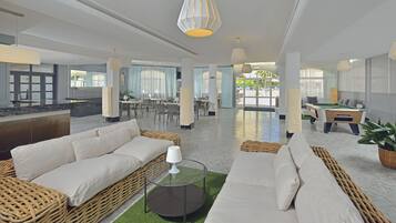 A spacious lobby with a pool table, comfortable seating areas, and a dining setup.