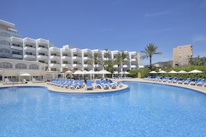 Relax by the resort pool surrounded by lounge chairs and umbrellas, with stunning views of the surrounding buildings and palm trees.