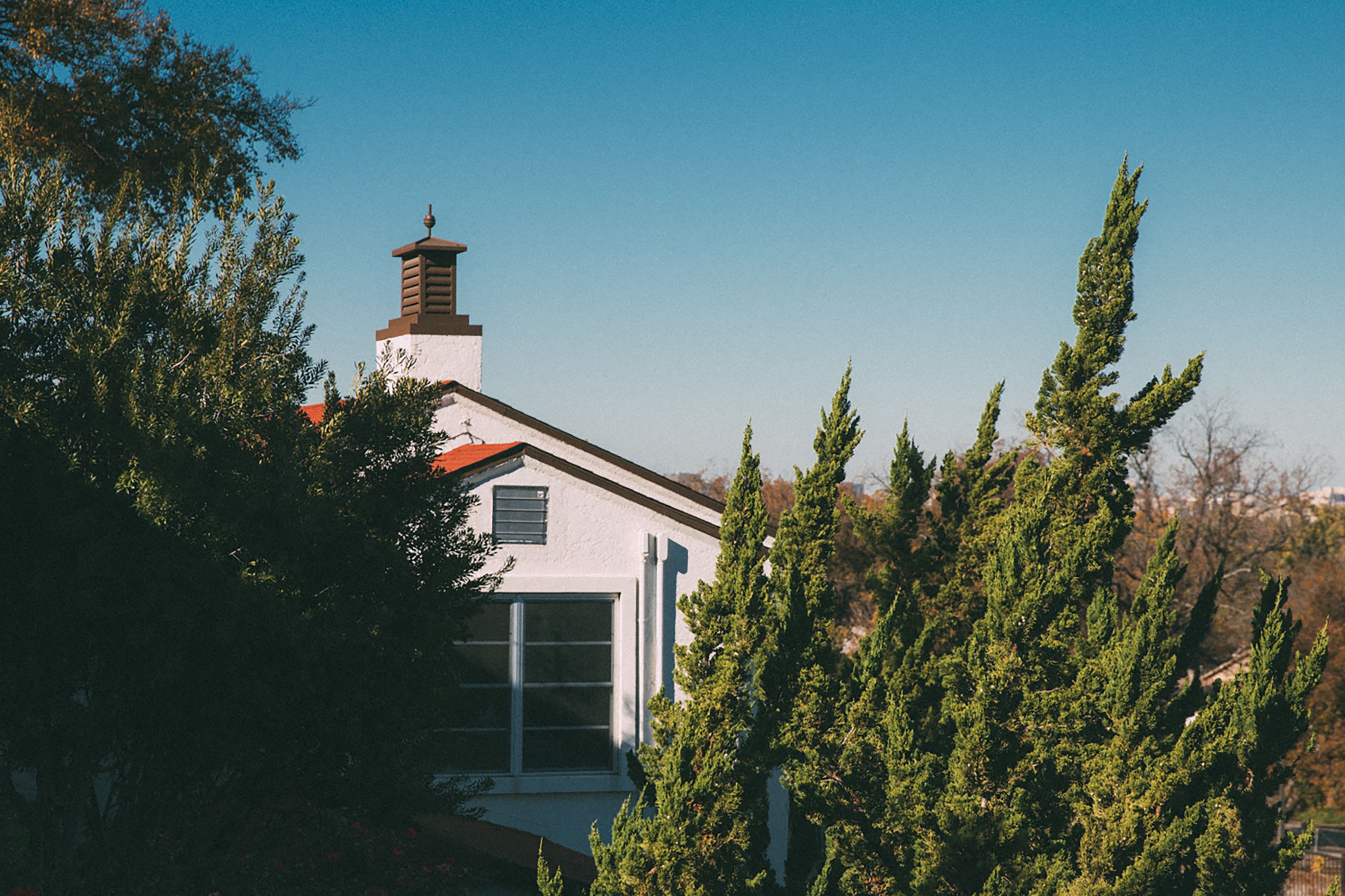 Una casa con techo rojo, paredes blancas y una chimenea.