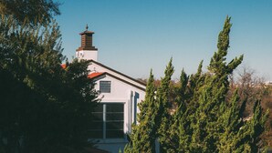 Une maison avec un toit rouge, des murs blancs et une cheminée.