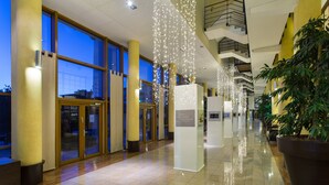 Un hall d’entrée spacieux, doté de grandes fenêtres, d’un sol réfléchissant et de luminaires suspendus.