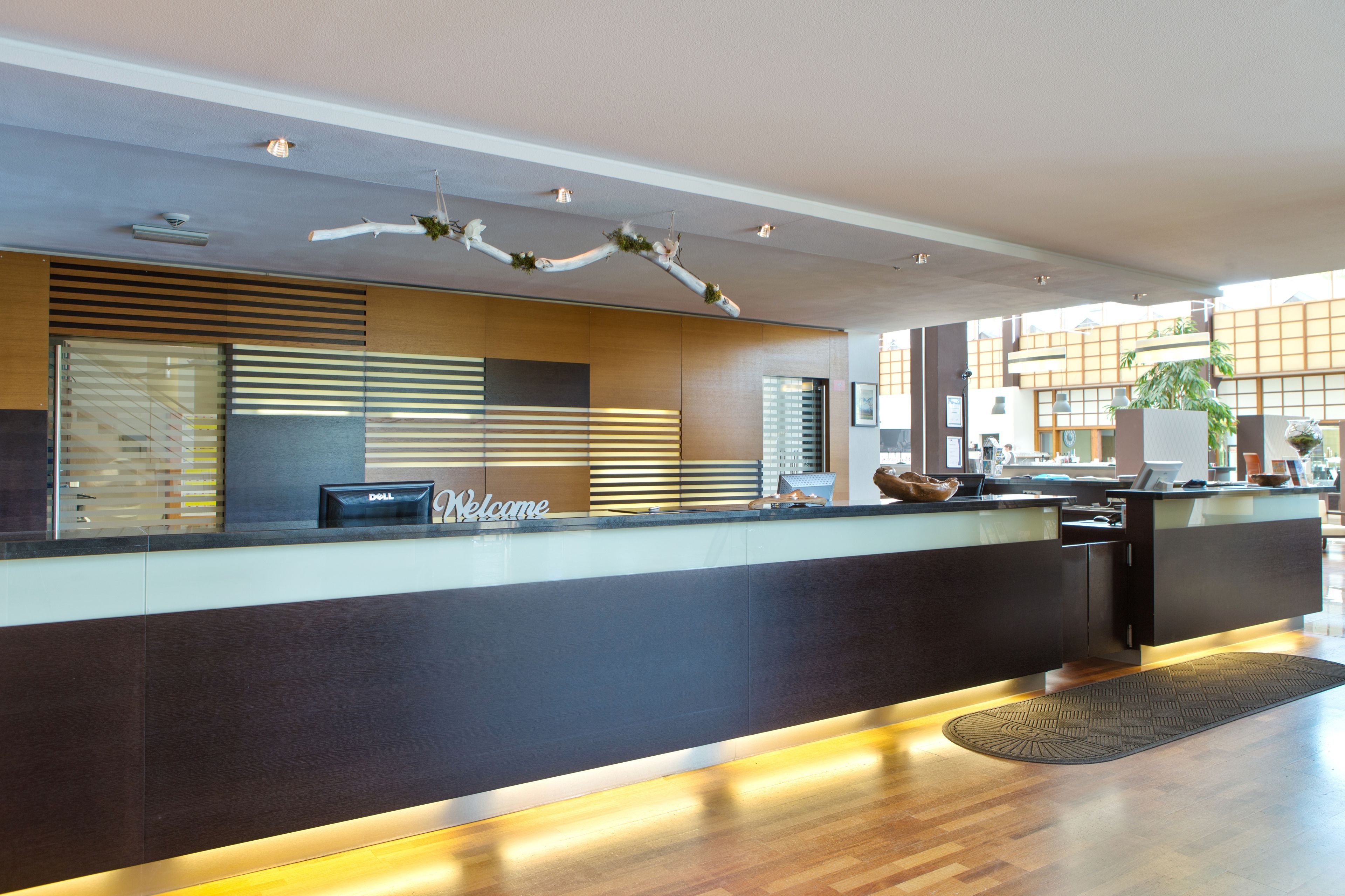A modern reception desk with a 'Welcome' sign, a Dell computer, and a decorative ceiling.