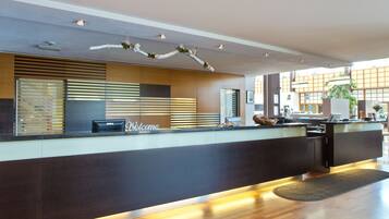 A modern reception desk with a 'Welcome' sign, a Dell computer, and a decorative ceiling.