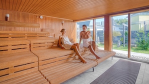 Un sauna avec des bancs en bois et de grandes fenêtres.