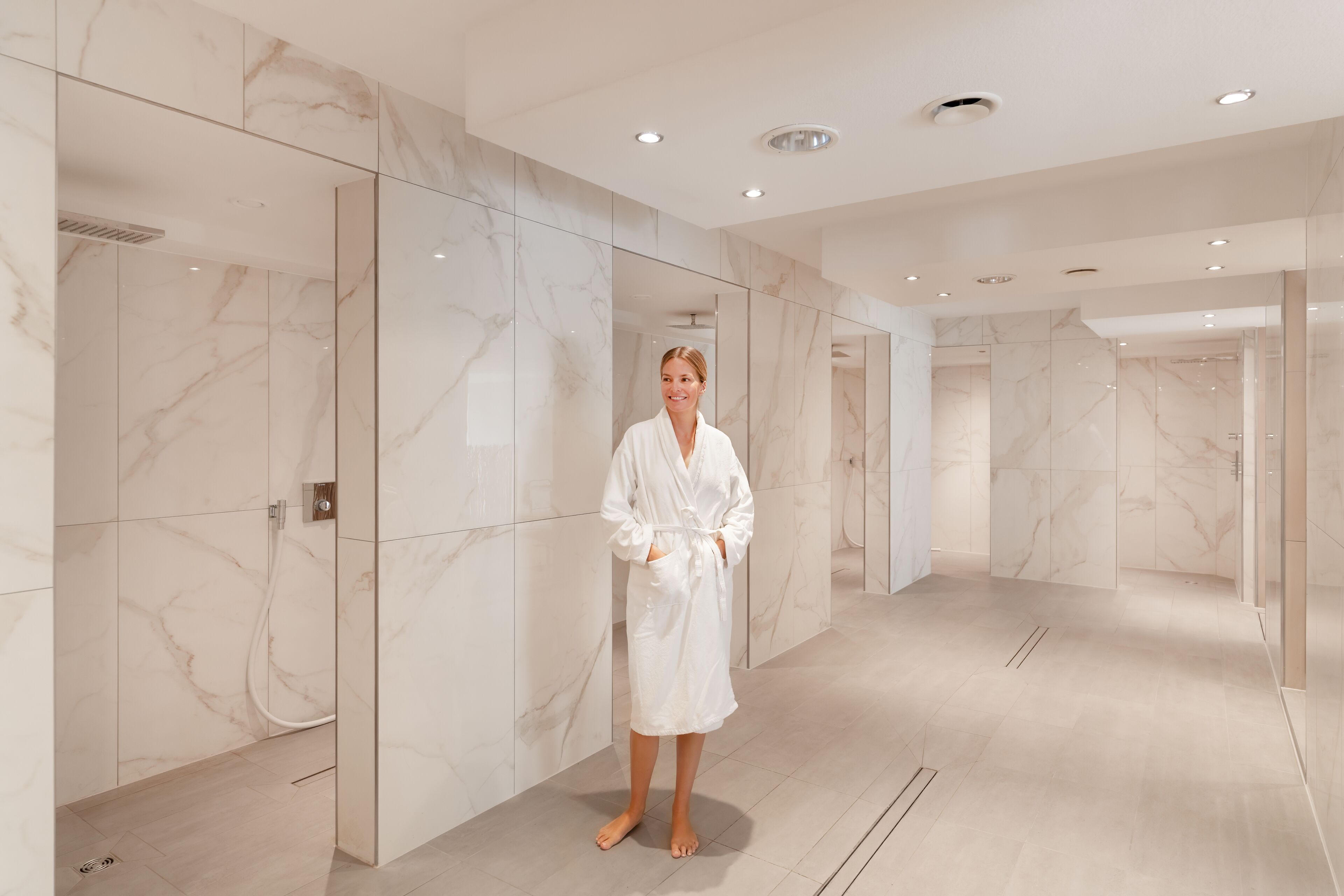 A modern bathroom with marble walls and a glass shower enclosure.