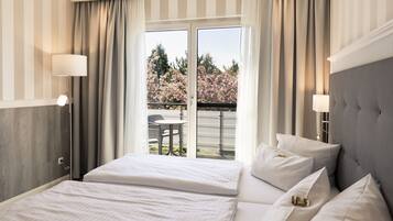 Habitación de hotel con una cama grande, dos lámparas de noche y vistas a un balcón lleno de flores de cerezo.