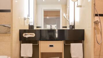 A modern bathroom with a black countertop, a mirror, a towel rack, and a shower.
