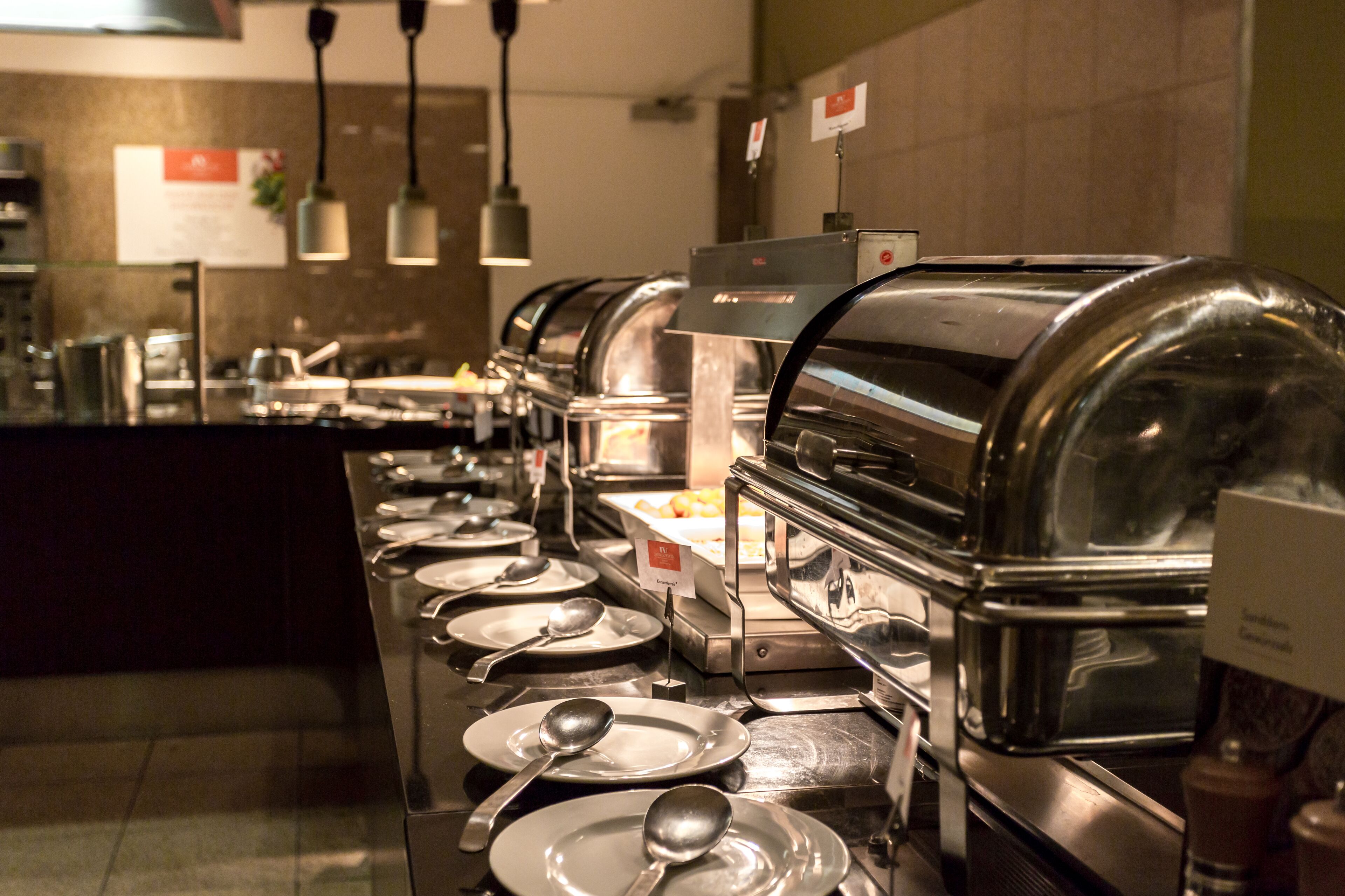 Ein reichhaltiges Buffet mit mehreren Selbstbedienungsstationen, jeweils mit Glaskuppel, Serviertabletts und Besteck ausgestattet.