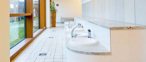 A modern bathroom with a large window, a sink, and a potted plant.