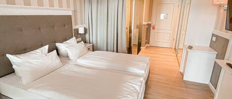 A hotel room with a large bed, a bedside table, a lamp, and a mirror.