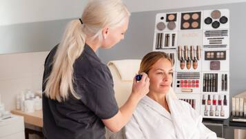 A person receiving a facial treatment in a room with a wall displaying various cosmetic products.