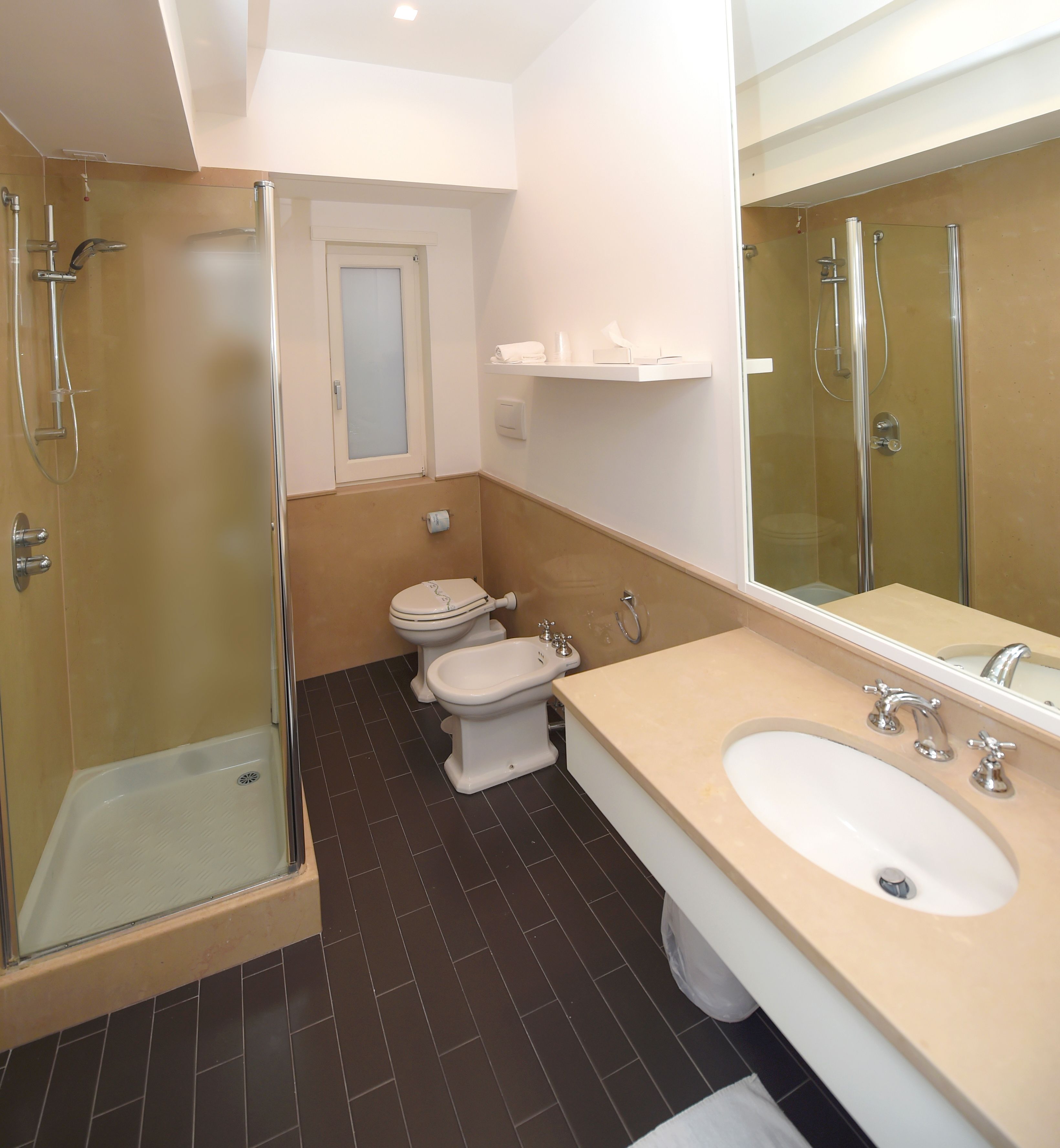 Een moderne badkamer met een douchecabine van glas, een toilet en een wastafel met een grote spiegel.