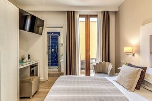 A hotel room with a bed, a desk with a computer, a chair, a TV, and a bathroom visible through an open door. - Hotel Sorrento City (Sorrento)