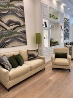A modern living room with a beige sofa, a green armchair, and a large abstract painting on the wall.
