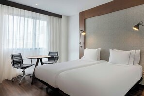 A hotel room with two beds, a dining table, and chairs.
