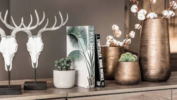 A wooden shelf with decorative items including a book titled 'Palais Duane Michaels', a small potted plant, and two metal sculptures resembling antlers.