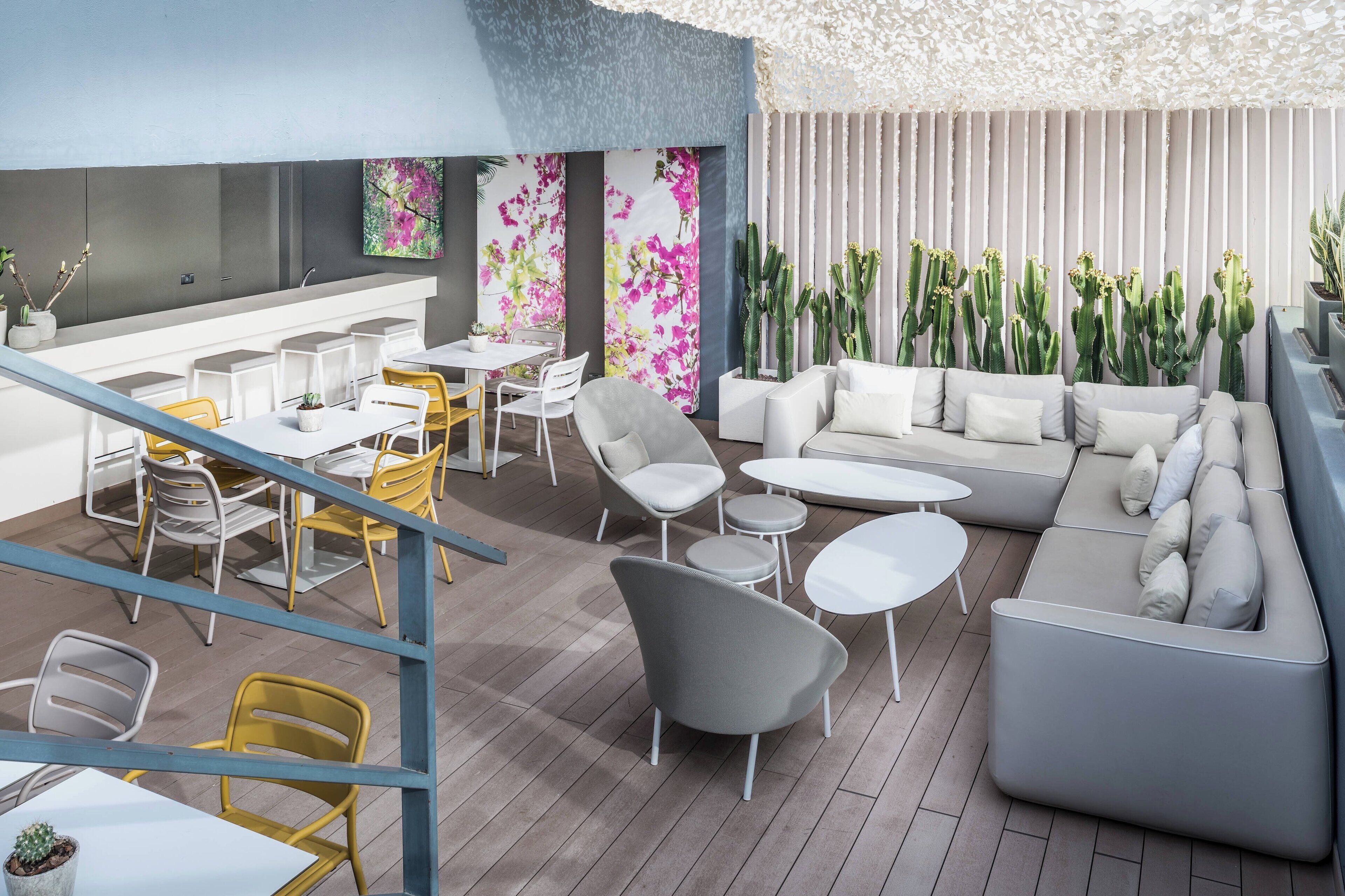 A modern lounge area with a bar, seating arrangements, and decorative plants.