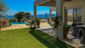 Eine überdachte Terrasse im Freien mit Pool, Liegestühlen und Meerblick.
