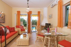 A living room with a glass table, wicker furniture, and a sofa with red cushions.