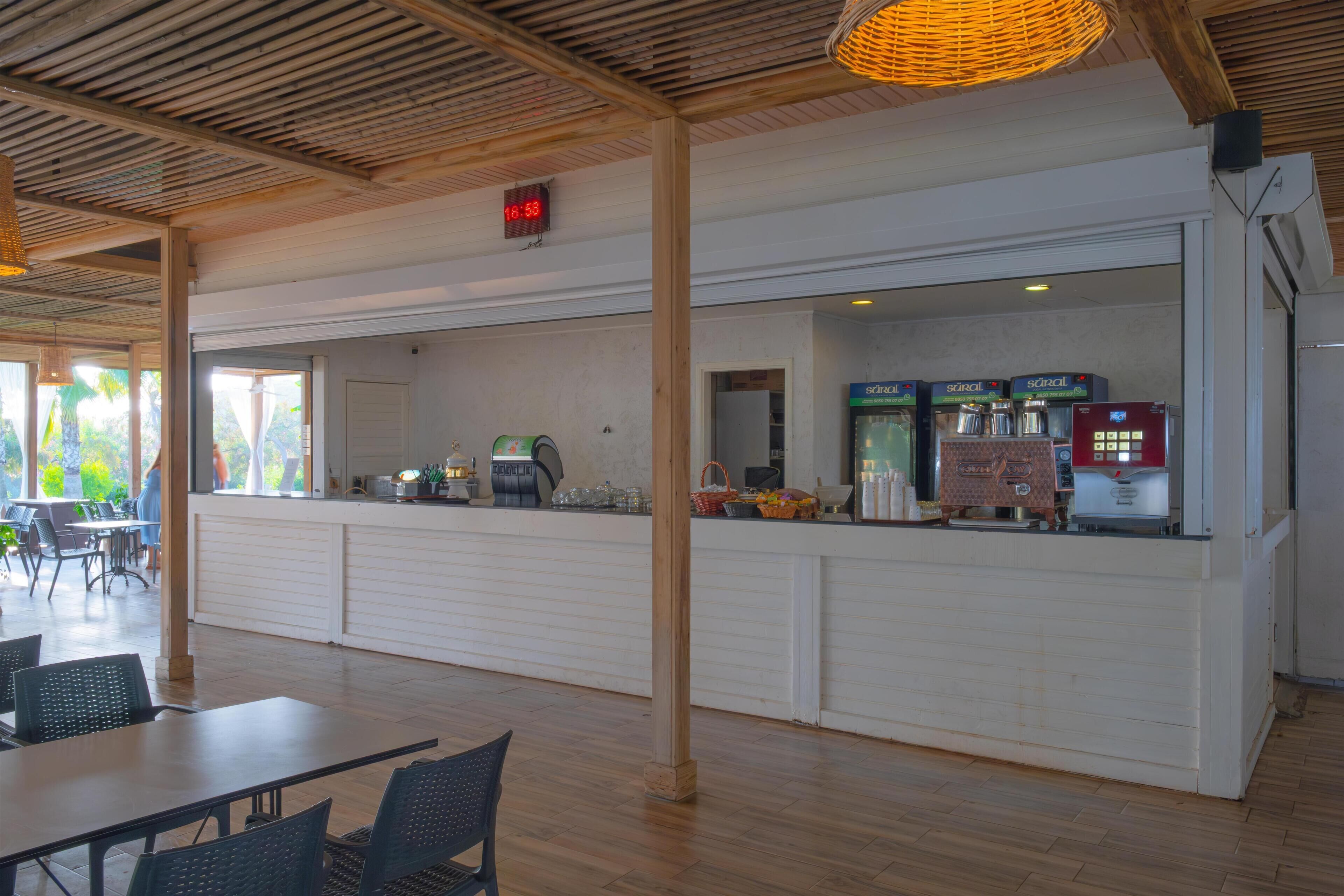 A spacious indoor area with a long counter, seating, and a clock displaying 10:53.